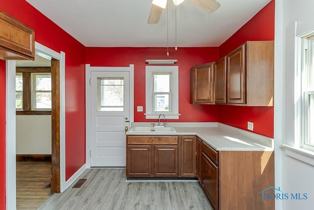 kitchen with brown cabinets, light countertops, light wood finished floors, and a sink