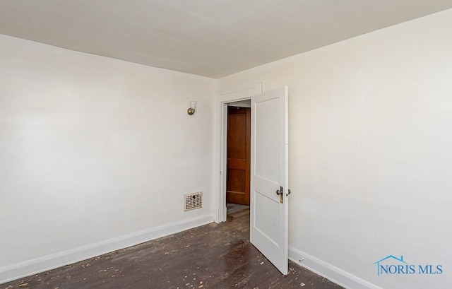 empty room with baseboards, visible vents, and wood finished floors