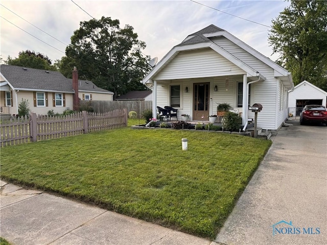 bungalow with covered porch, fence, an outdoor structure, a front yard, and a detached garage
