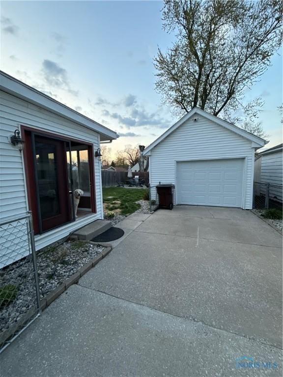 exterior space featuring driveway, an outbuilding, fence, and a detached garage