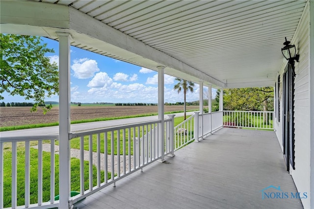 deck featuring covered porch, a rural view, and a yard