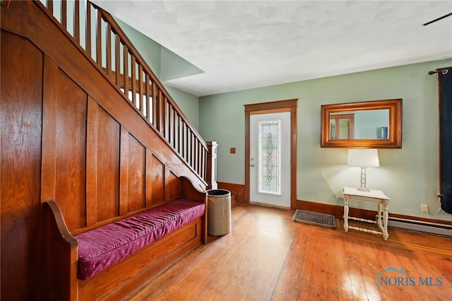 entrance foyer with baseboards, stairway, baseboard heating, and light wood-style flooring