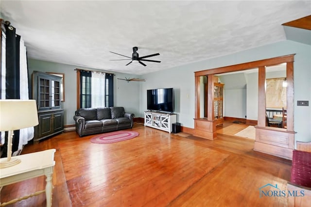 living area with baseboards, a ceiling fan, and wood finished floors