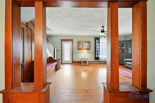 foyer entrance featuring baseboards, wood finished floors, a ceiling fan, and stairs