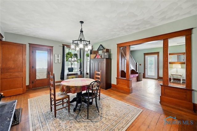 dining area with baseboards, stairs, a notable chandelier, and light wood-type flooring