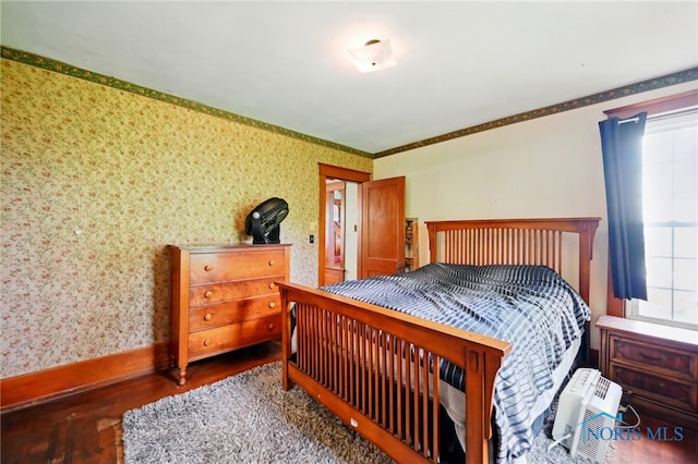 bedroom with wallpapered walls, wood finished floors, and baseboards