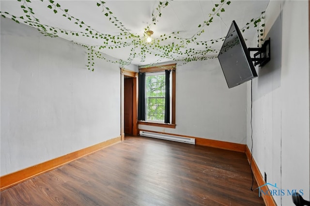 spare room with baseboards, a baseboard radiator, and wood finished floors