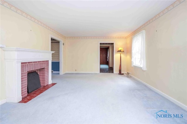 unfurnished living room with carpet flooring, a brick fireplace, and baseboards