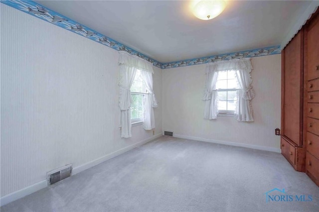 unfurnished room featuring light carpet, a wealth of natural light, and visible vents