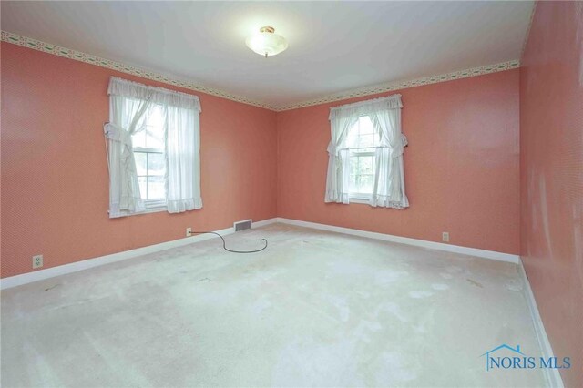 carpeted empty room with visible vents, baseboards, and a healthy amount of sunlight