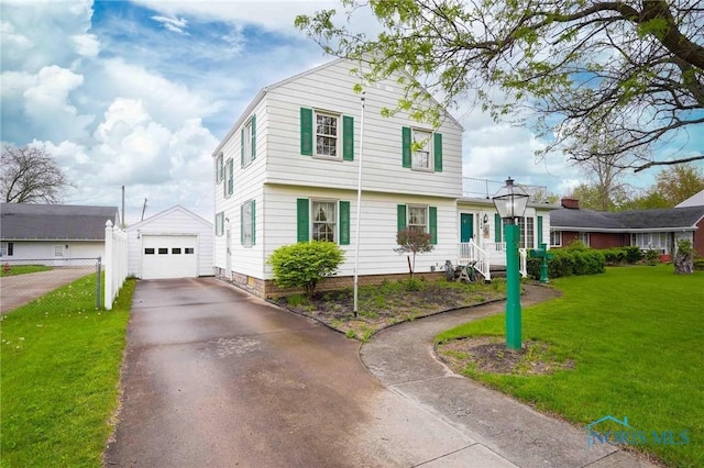 view of front of home featuring aphalt driveway, an outdoor structure, a detached garage, and a front lawn