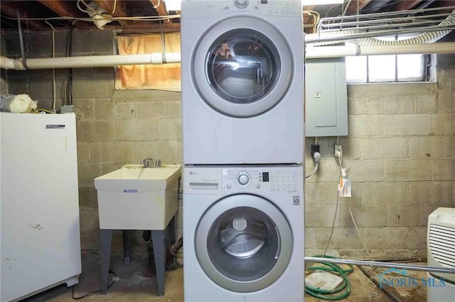 washroom with electric panel, laundry area, stacked washer / dryer, and a sink