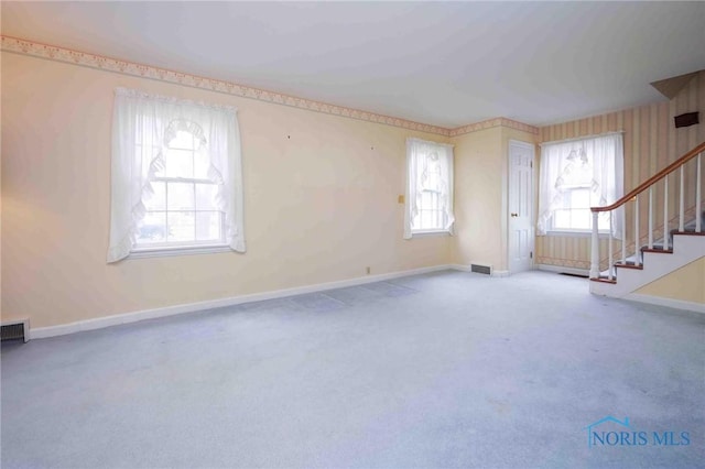 unfurnished living room with stairs, carpet, baseboards, and visible vents