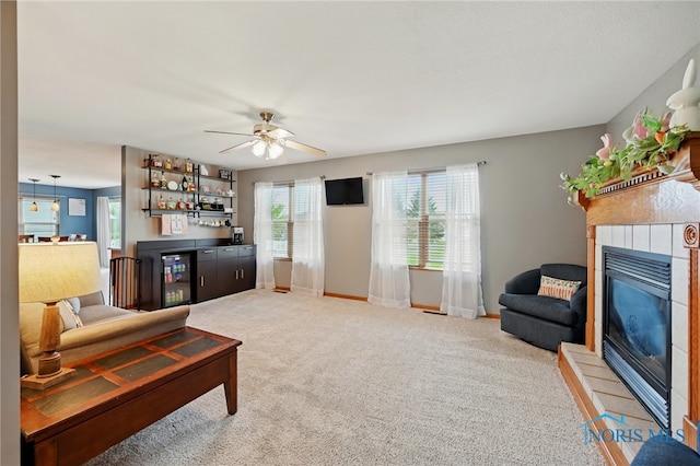living area with a bar, carpet, baseboards, ceiling fan, and a tile fireplace