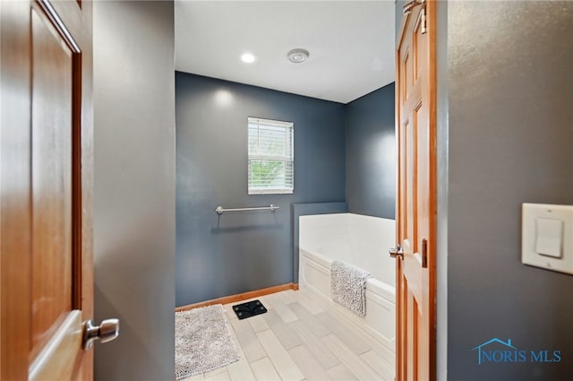 bathroom with a bath and baseboards