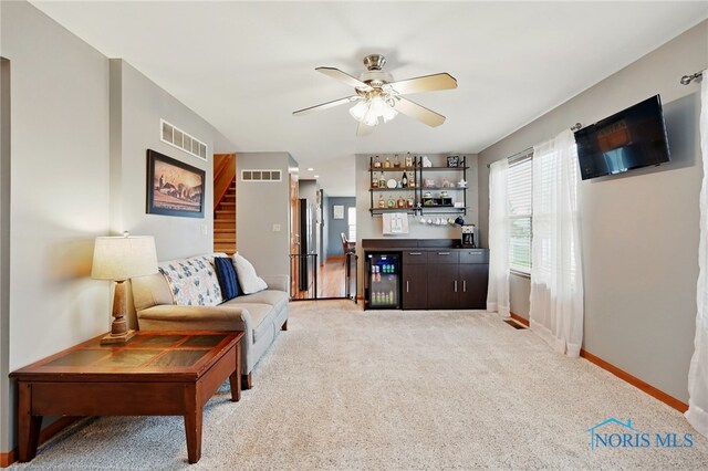 living area with beverage cooler, visible vents, baseboards, light colored carpet, and a dry bar