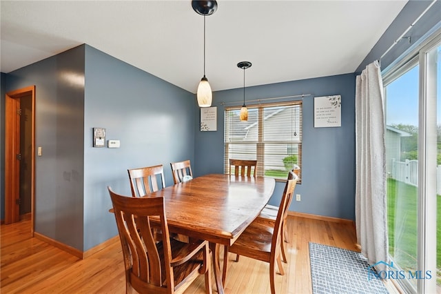 dining area with a wealth of natural light, baseboards, and light wood-type flooring