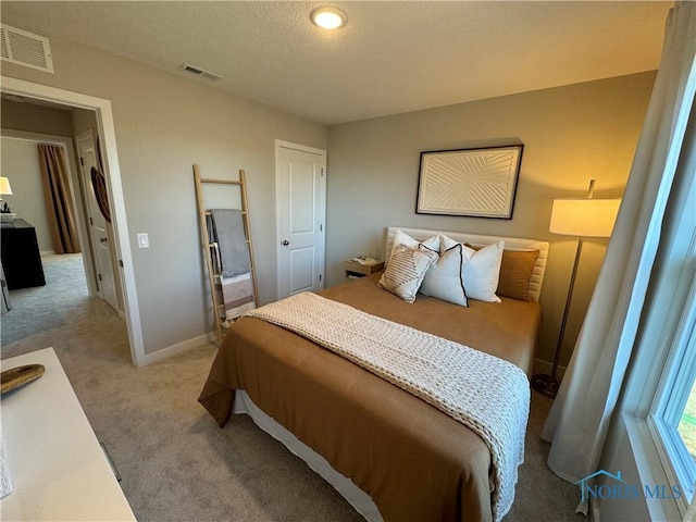 bedroom featuring a textured ceiling, carpet, baseboards, and visible vents