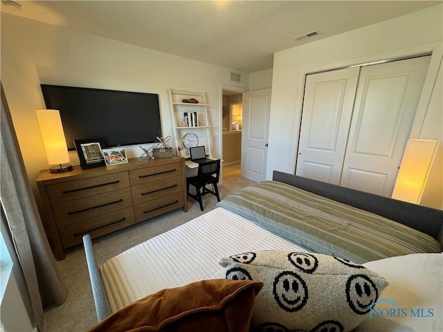 bedroom with a closet, visible vents, and light colored carpet