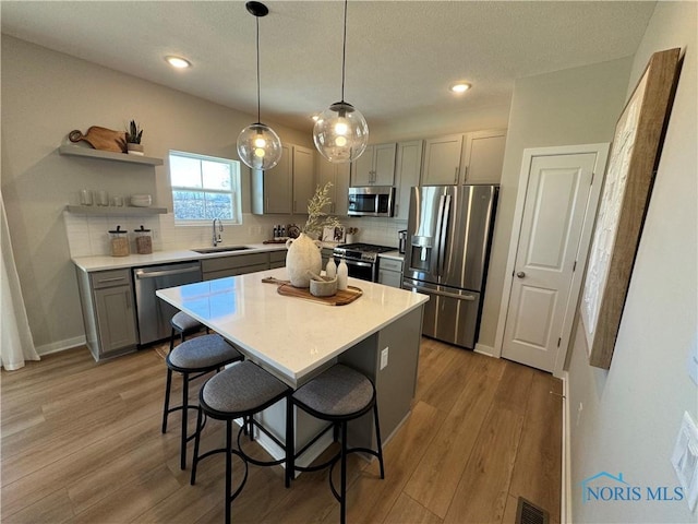 kitchen with gray cabinetry, appliances with stainless steel finishes, decorative backsplash, and a sink