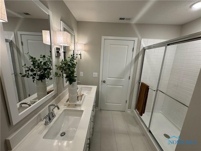 bathroom with a shower stall, visible vents, a sink, and double vanity