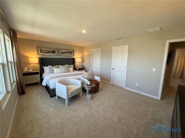 carpeted bedroom featuring a textured ceiling, visible vents, baseboards, and recessed lighting