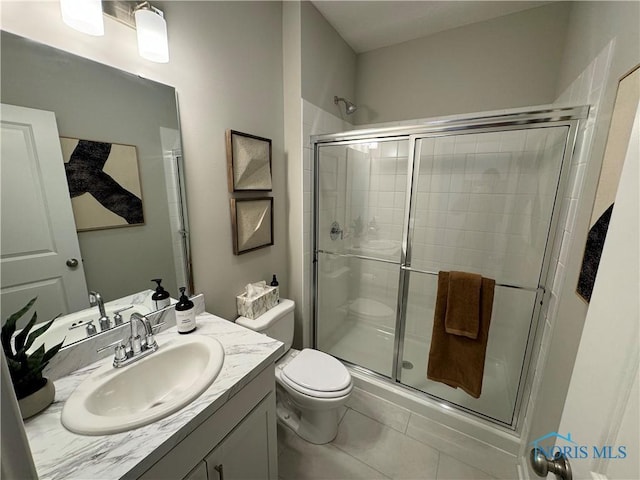bathroom with tile patterned floors, vanity, toilet, and a stall shower