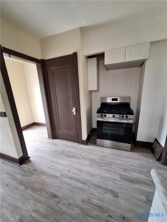 kitchen featuring stainless steel gas range, light wood finished floors, and baseboards