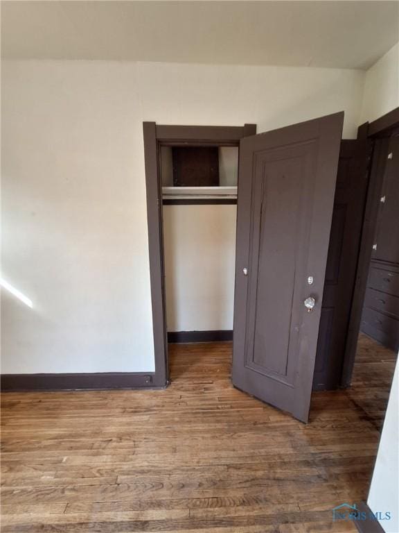 unfurnished bedroom featuring baseboards, a closet, and wood finished floors