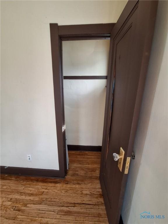 corridor with baseboards and wood finished floors