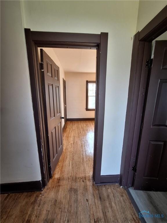 hallway featuring baseboards and wood finished floors