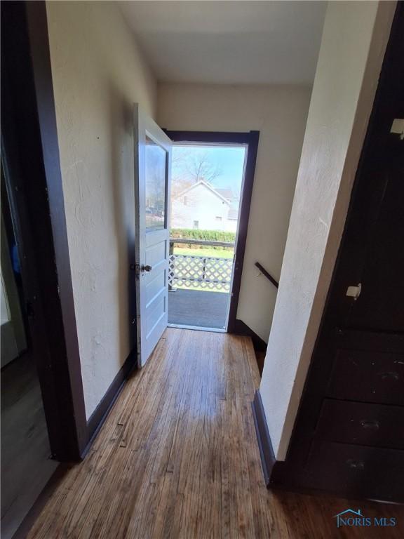 doorway featuring baseboards and wood finished floors