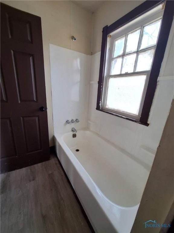 bathroom with washtub / shower combination and wood finished floors
