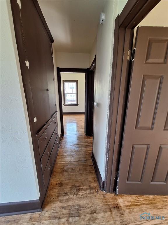 hallway featuring baseboards and wood finished floors