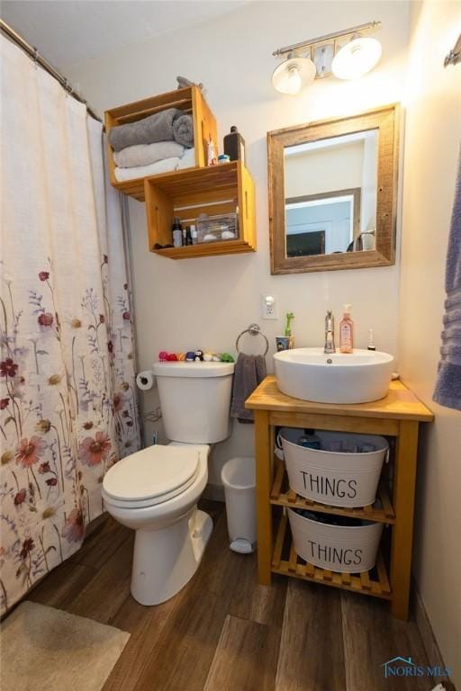 bathroom with wood finished floors, toilet, vanity, and a shower with curtain