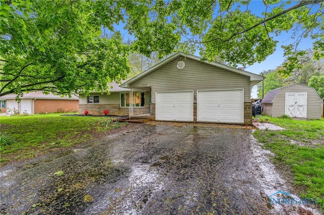 ranch-style home with a shed, driveway, an attached garage, an outbuilding, and a front yard