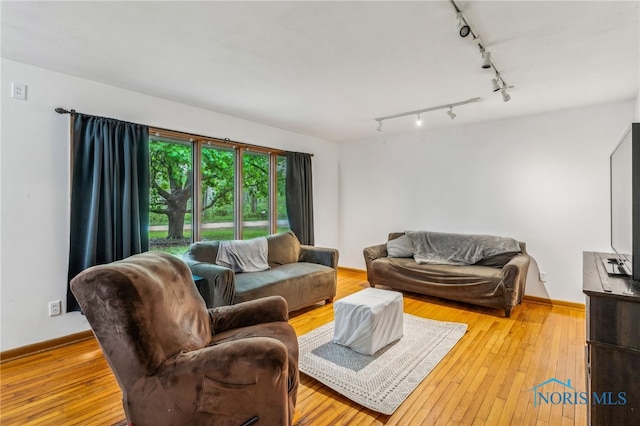 living room featuring track lighting, hardwood / wood-style floors, and baseboards