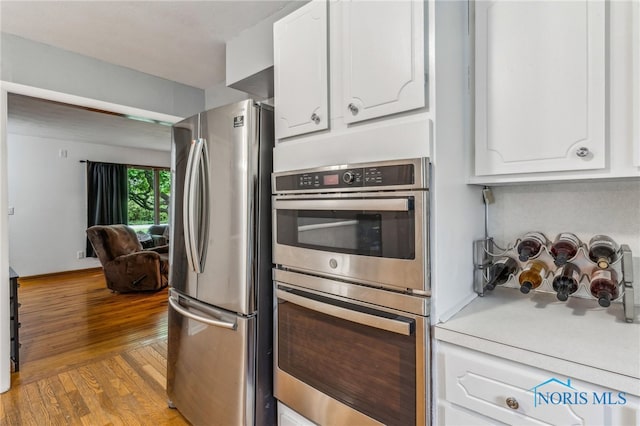 kitchen featuring stainless steel appliances, white cabinetry, light wood finished floors, and light countertops