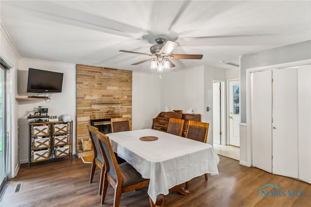 dining area featuring a ceiling fan, wood finished floors, a fireplace, and healthy amount of natural light