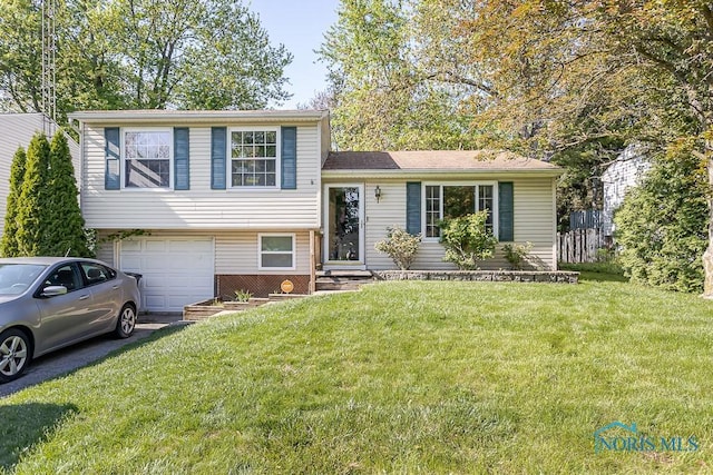 split level home featuring an attached garage, driveway, a front yard, and entry steps