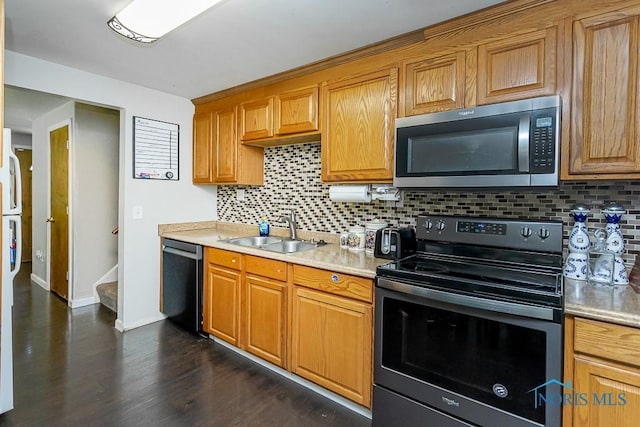 kitchen with appliances with stainless steel finishes, a sink, backsplash, and light countertops