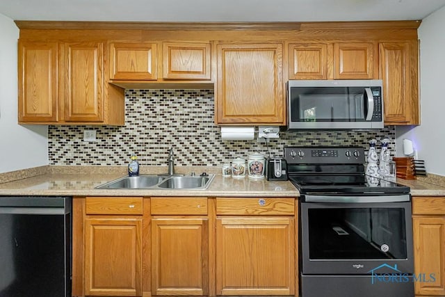 kitchen featuring appliances with stainless steel finishes, a sink, light countertops, and tasteful backsplash