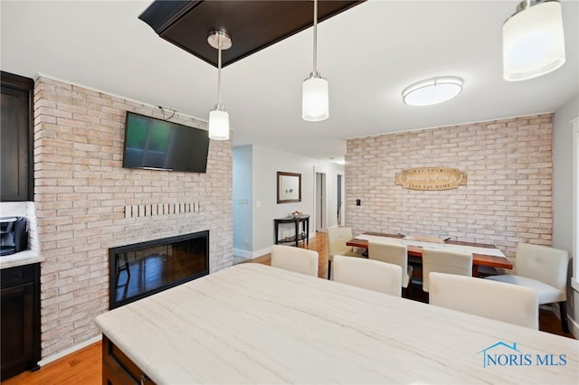 685 N Main St, Arlington, OH 45814 - dining area with a fireplace, light wood-type flooring, and brick wall