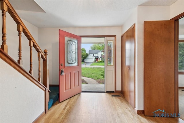 entryway featuring light wood-style floors, baseboards, and stairway