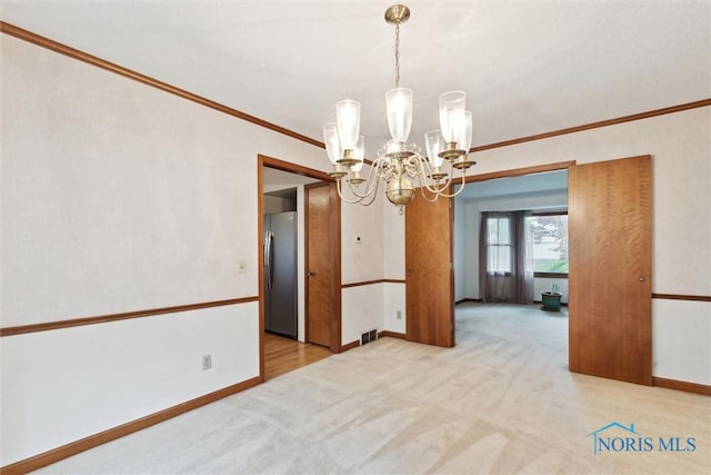 empty room with a chandelier, ornamental molding, light colored carpet, and baseboards