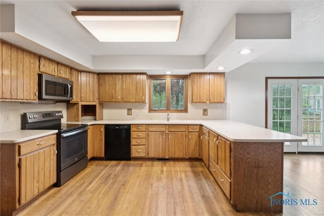 kitchen with stainless steel microwave, dishwasher, electric range oven, a peninsula, and light countertops