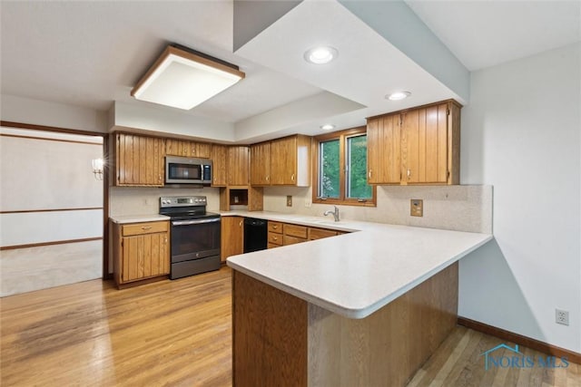 kitchen featuring electric stove, stainless steel microwave, light countertops, baseboards, and light wood-style floors