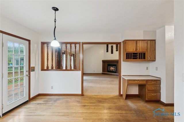 unfurnished dining area featuring wood finished floors, baseboards, and a glass covered fireplace
