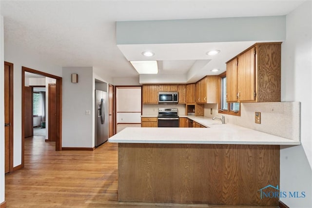 kitchen with stainless steel appliances, healthy amount of natural light, light countertops, a peninsula, and recessed lighting