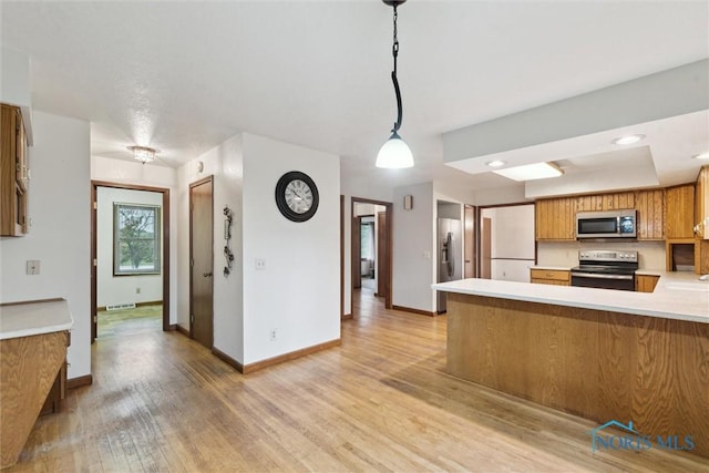 kitchen with stainless steel appliances, light wood-style flooring, light countertops, baseboards, and brown cabinets